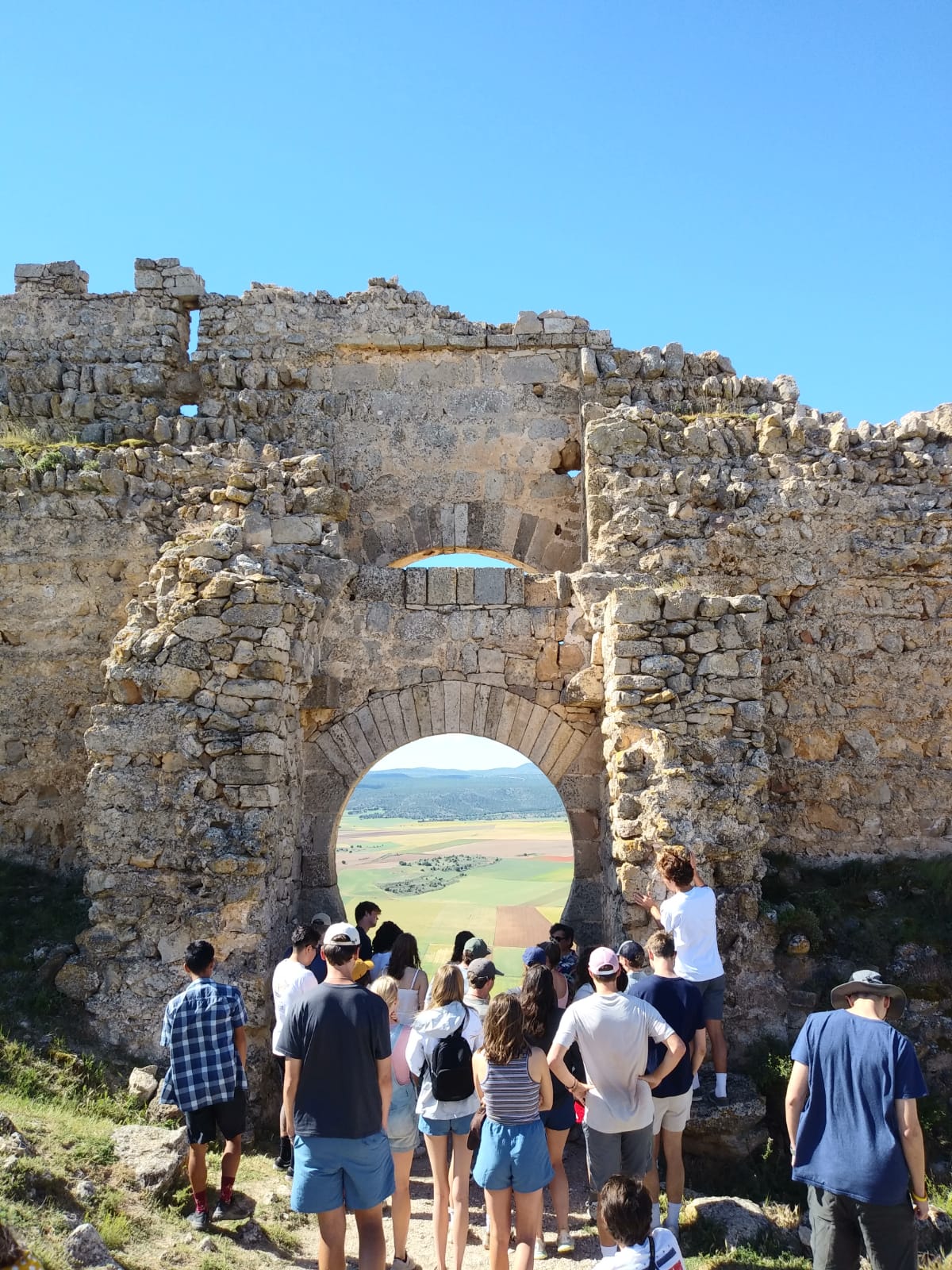 A small opening provides a window for students to look past the castle wall of Castillo de Gormaz and onto the farmlands below 